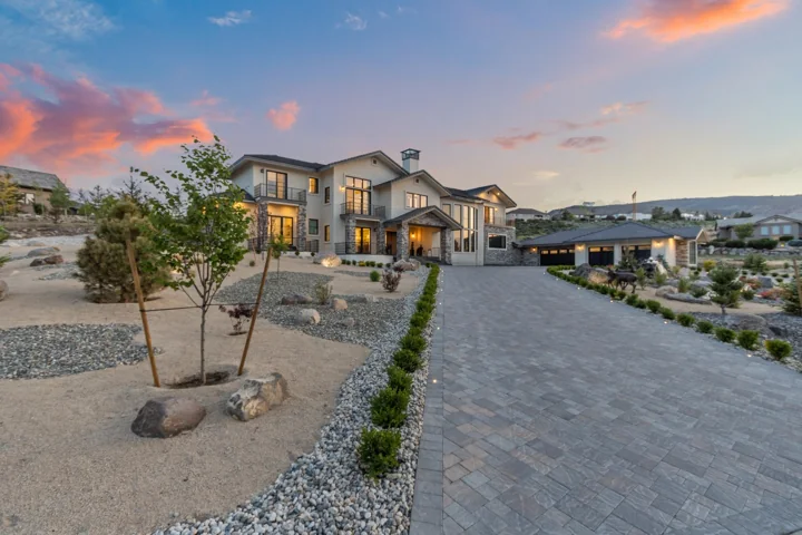 Two-story home and paver driveway at dusk
